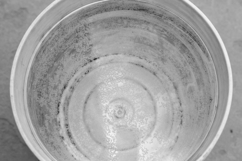 Industry and Violation of Human Right to Water - Water in a bucket filäed with water sourced from the local tubewell-based pipeline supply in Bichhadi, Udaipur district, Rajasthan, showing a thin greasy top layer having particulate matter